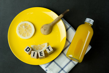 Bottle of fresh orange juice with slice fresh lemon on yellow plate