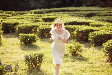 Inspired cheerful young woman millenial in light peasant dress runs across green grass through...