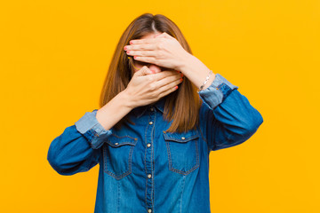 young pretty woman covering face with both hands saying no to the camera! refusing pictures or...