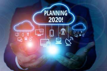 Text sign showing Planning 2020. Business photo showcasing process of making plans for something next year Male human wear formal work suit presenting presentation using smart device