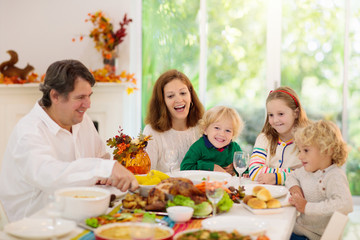 Family with kids at Thanksgiving dinner. Turkey.