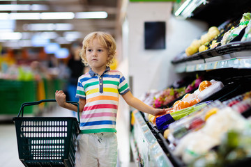 Child in supermarket. Kid grocery shopping.