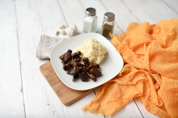Sesame beef dish on a white wood background served with mashed potatoes and seasonings