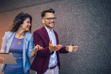 Handsome man and beautiful woman as business partners using digital tablet outdoor