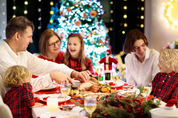 Family with kids having Christmas dinner at tree