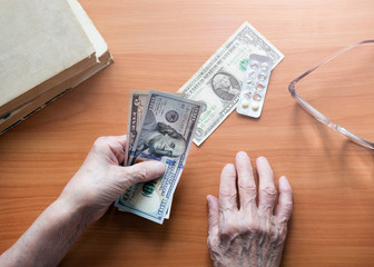 Dollar bills in the hands of a pensioner. An elderly retired woman counts money. The concept of financial problems among pensioners. Banknotes in the hands of an old woman.