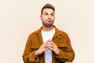 young hispanic man scheming and conspiring, thinking devious tricks and cheats, cunning and...