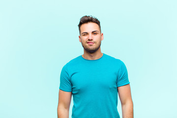 young hispanic man looking happy and friendly, smiling and winking an eye at you with a positive...
