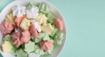 Ceramic vase full of colorful merengues at pastel mint background