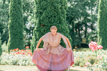 Obraz na płótnie Canvas Young graceful female ballet dancer in theatrical dress posing in sunny park