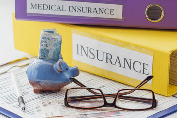 Clean insurance form, folders, pen, piggy bank and glasses