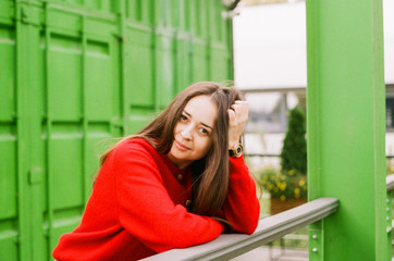 Brunette with long hair in a red sweater on a green background