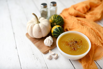 Pumpkin vegetable soup on white wooden backdrop and seasonings. Fall harvest soup 
