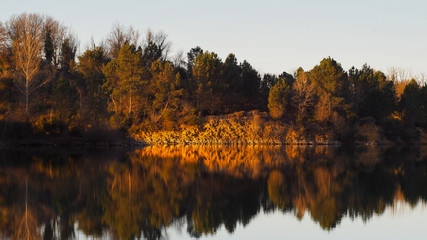 Reflets de rochers sur un étang, pendant l'heure dorée