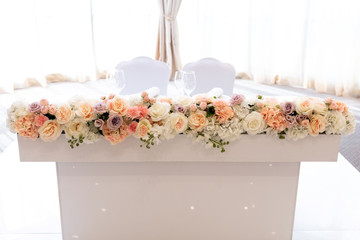 The table of newlyweds is rectangular and white decorated with fresh colors of pastel shades.