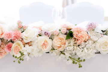 A beautiful bouquet on an elongated wedding table made of roses of different shades