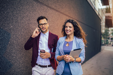 Handsome man and beautiful woman as business partners using digital tablet outdoor