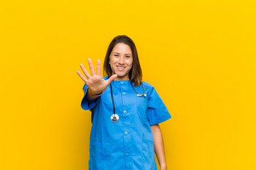 smiling and looking friendly, showing number five or fifth with hand forward, counting down...
