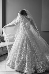 Portrait of beautiful bride in white vintage dress  posing under veil in studio