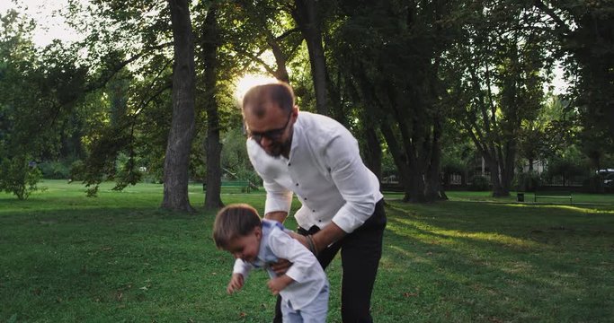 Young dad with his small son enjoying the time together playing and have fun in the middle of the park