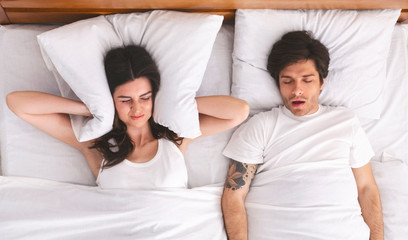 Irritated woman can't sleep because of her boyfriend snoring