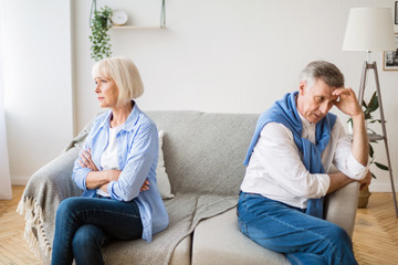Senior couple after argument sitting on opposite sides of sofa