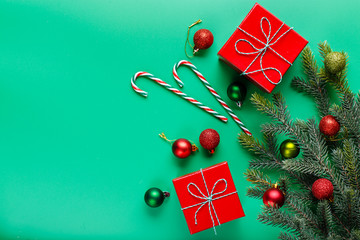 Christmas gifts in red boxes, green and red Christmas balls, candy-canes and Christmas tree branch