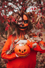 Young blonde girl with halloween face art posing outdoor.  Helloween celebration concept.