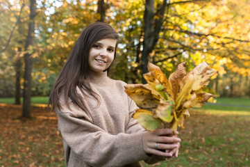 Fototapeta Uśmiechnięta dziewczyna trzyma liście w rękach. obraz