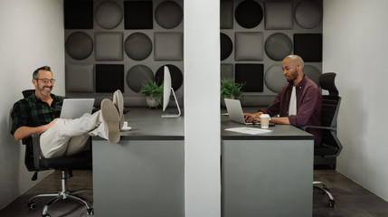 Two business entrepreneurs working in cubicle workstations in coworking office space