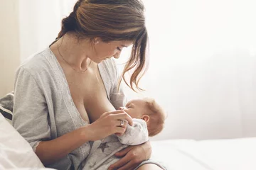 Fototapeten Loving mom breastfeeding her newborn baby at home © Alena Ozerova
