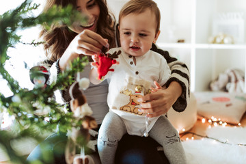 Mother and baby playing around the Christmas Tree