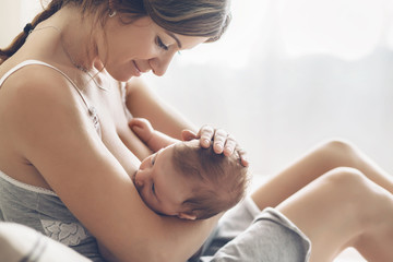 Loving mom breastfeeding her newborn baby at home