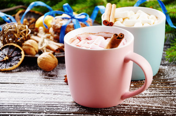 Christmas background of two mugs of hot chocolate with marshmallows, spruce branch and tray with gingerbread cookies on wooden table
