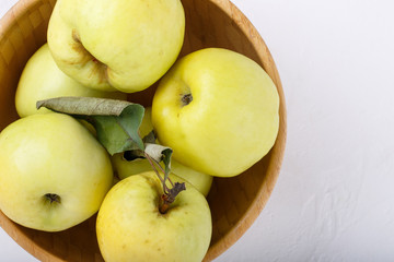 Ripe  yellow apples in wooden bowl isolated on white background. Antonovka apples. Top view, close-up.