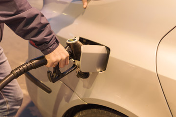 Male hand refilling the car with fuel on a filling station.