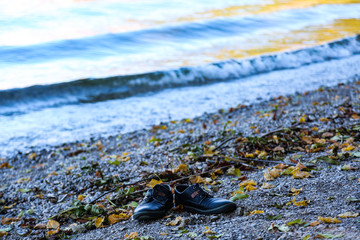 Shoes stand alone on the lake shore,