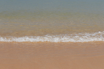 Sandy beach, scenic view to empty sea coast with yellow sand and clear wave with white foam. Picturesque tropical seascape
