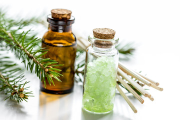 Spruce needle aromatherapy essential oils and salt in bottles on white table background
