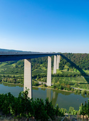 View on high freeway viaduct bridge across Mosel river valley and terraced vineyards, road network...