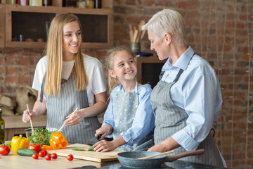 Adult cheerful ladies teaching little girl how to cook