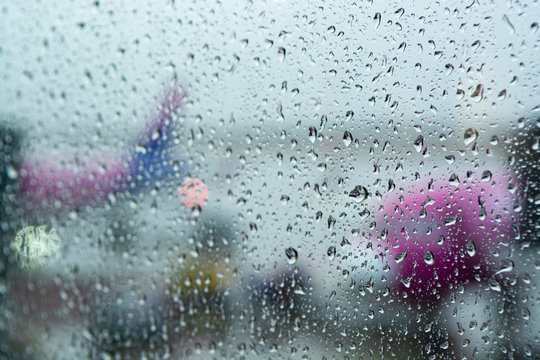 Travel in bad weather conditions concept background with water drops on window with blurred view on airplanes