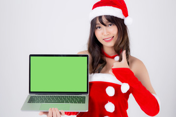 beautiful young asian woman in Santa presenting laptop computer in Christmas holiday isolated on white background, asia girl showing notebook and pointing for celebrating in xmas day or new year.