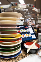 a stack of the various color plate at a sushi restaurant