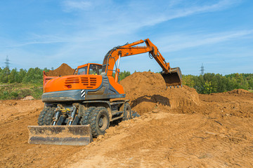 The modern excavator performs excavation work on the construction site.