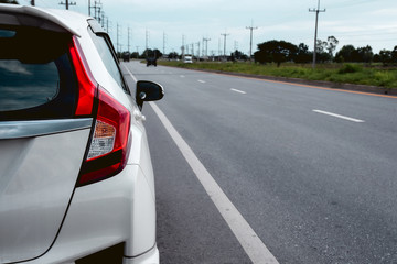 Rear view of new white hatchback car parking on roadside. - obrazy, fototapety, plakaty