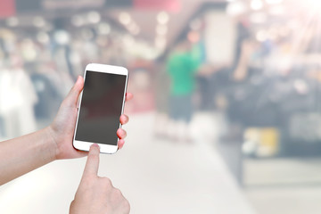 hand holding mobile smart phone with shopping mall blurred background