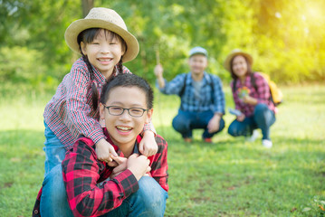 Happy asian siblings smiling with their father and mother sitting in background.