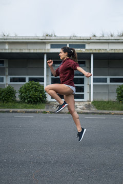Female athlete running and jumping. Sporty young woman soing technique exercise on asphalt.