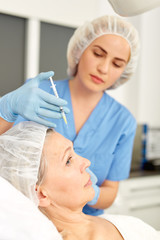 Senior woman getting injection for facial rejuvenation procedure in esthetic clinic